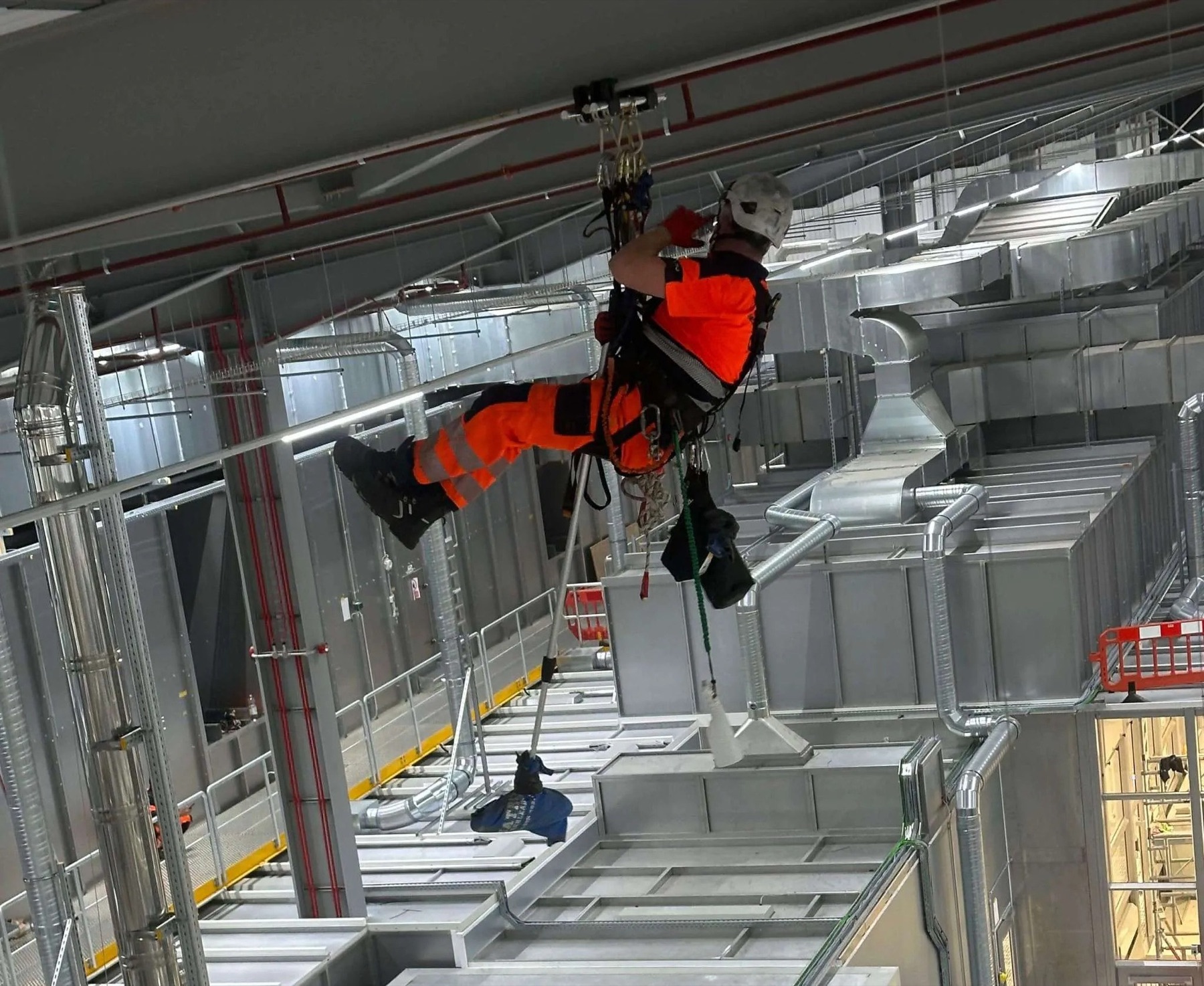 Technician suspended above industrial ductwork