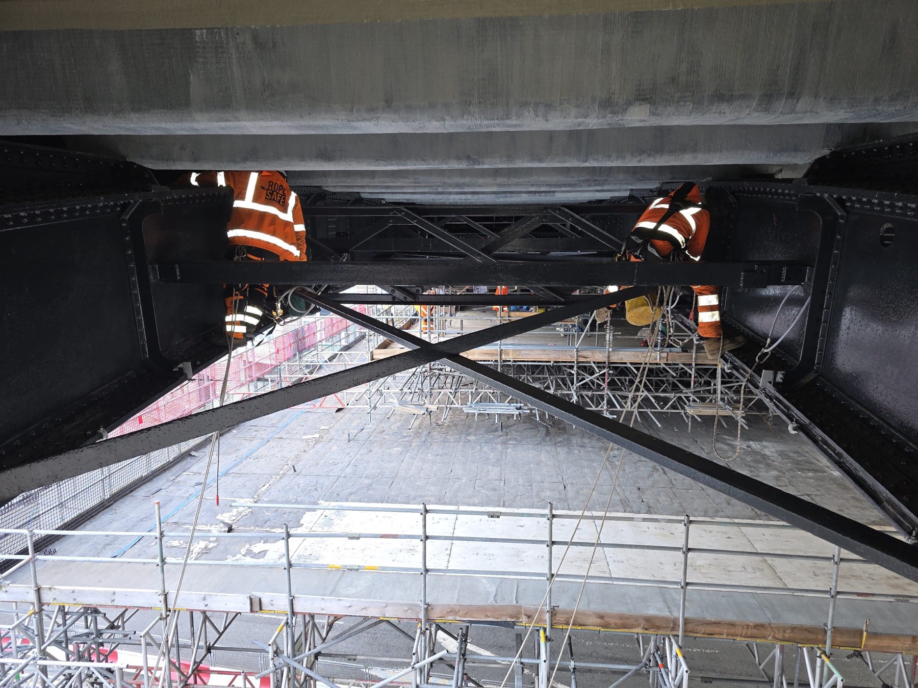 Technicians working on the underside of a steel structure